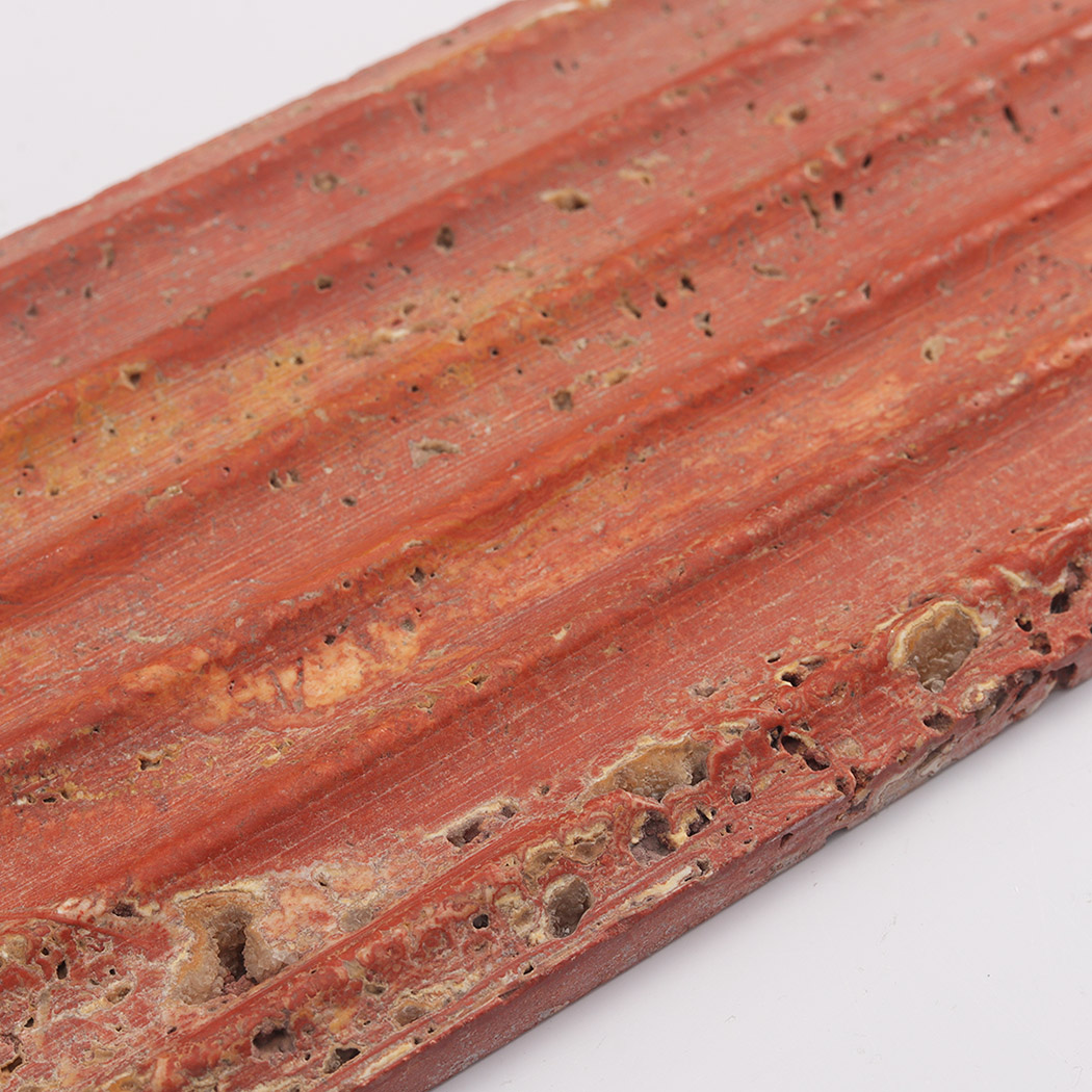 Close up of red travertine fluted tile with porous stone texture
