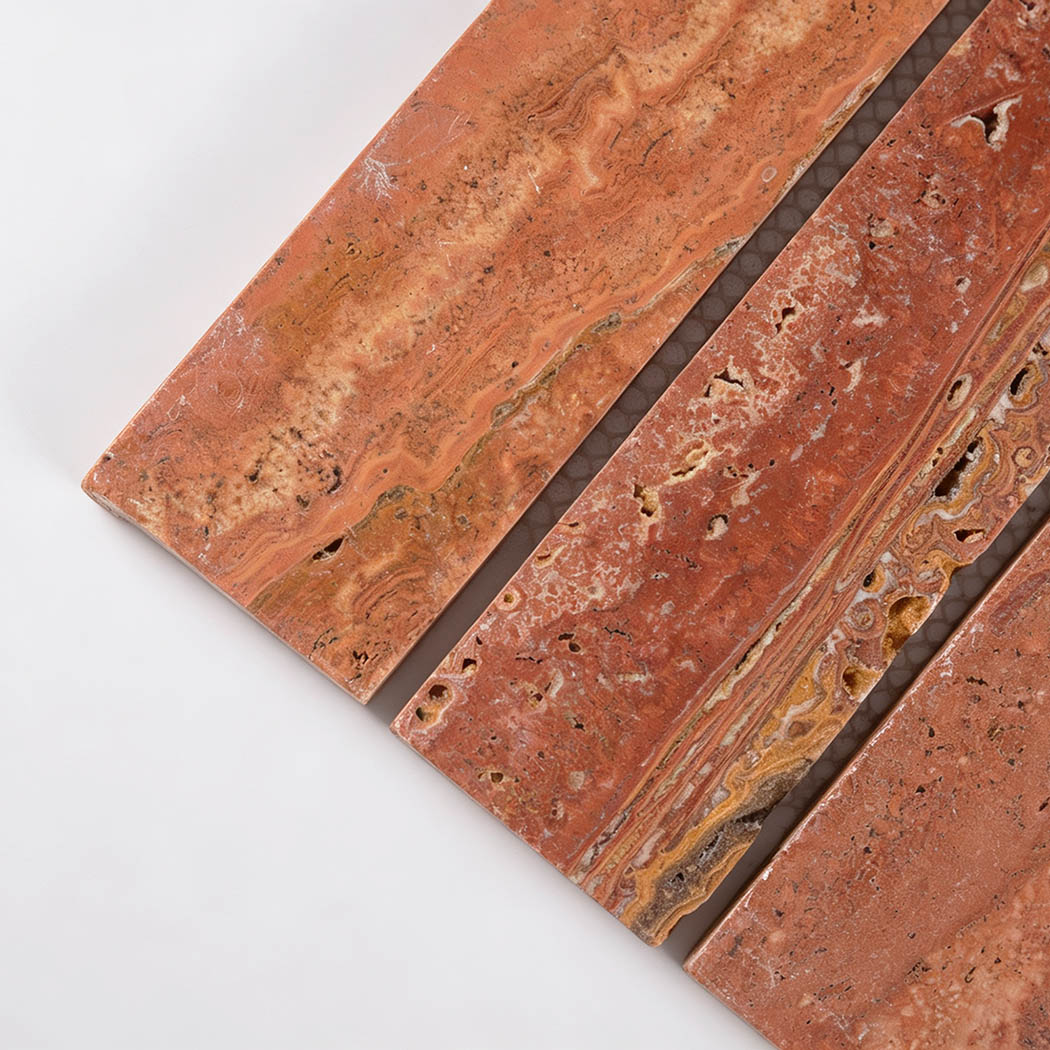 Close-up of red travertine strips with layered patterns and natural pores