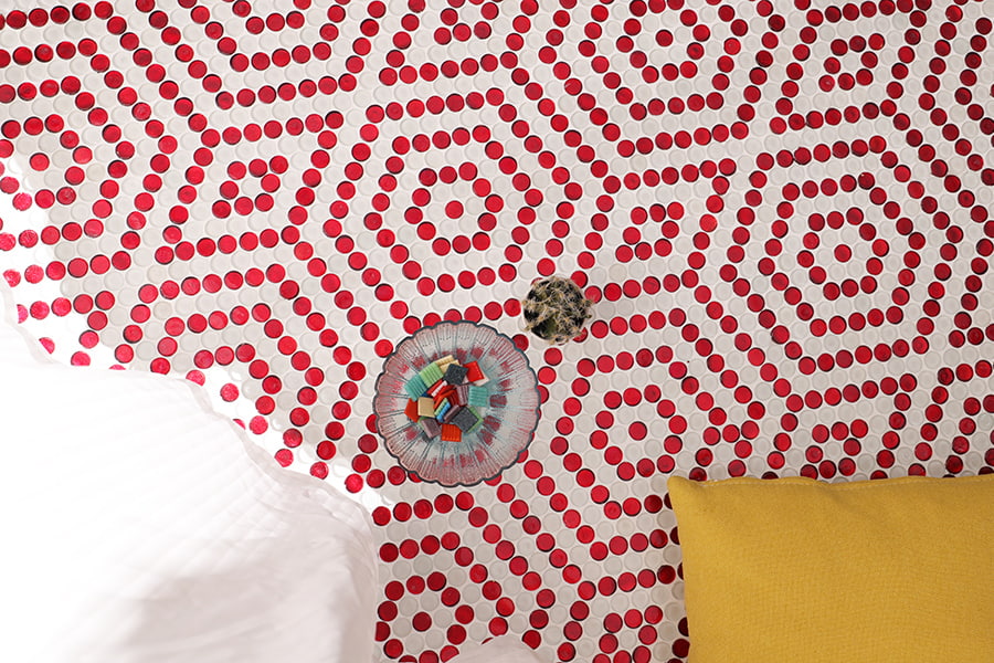 Top-down shot of red and white penny round tiles in a hexagon layout with a yellow pillow 