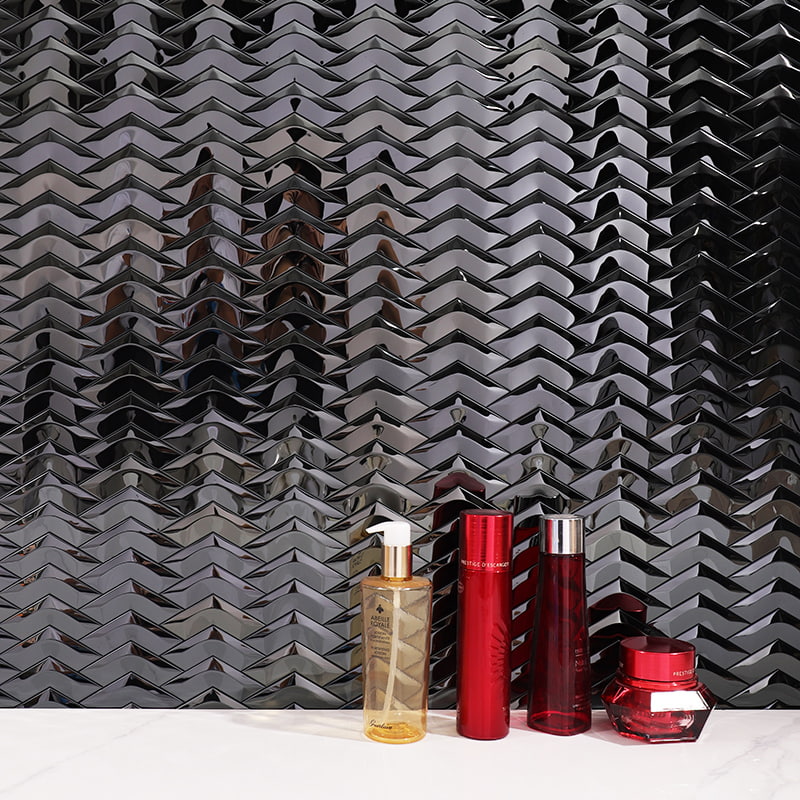Reflective steel chevron tile backdrop with gold-pump and red cosmetic bottles on marble ledge.
