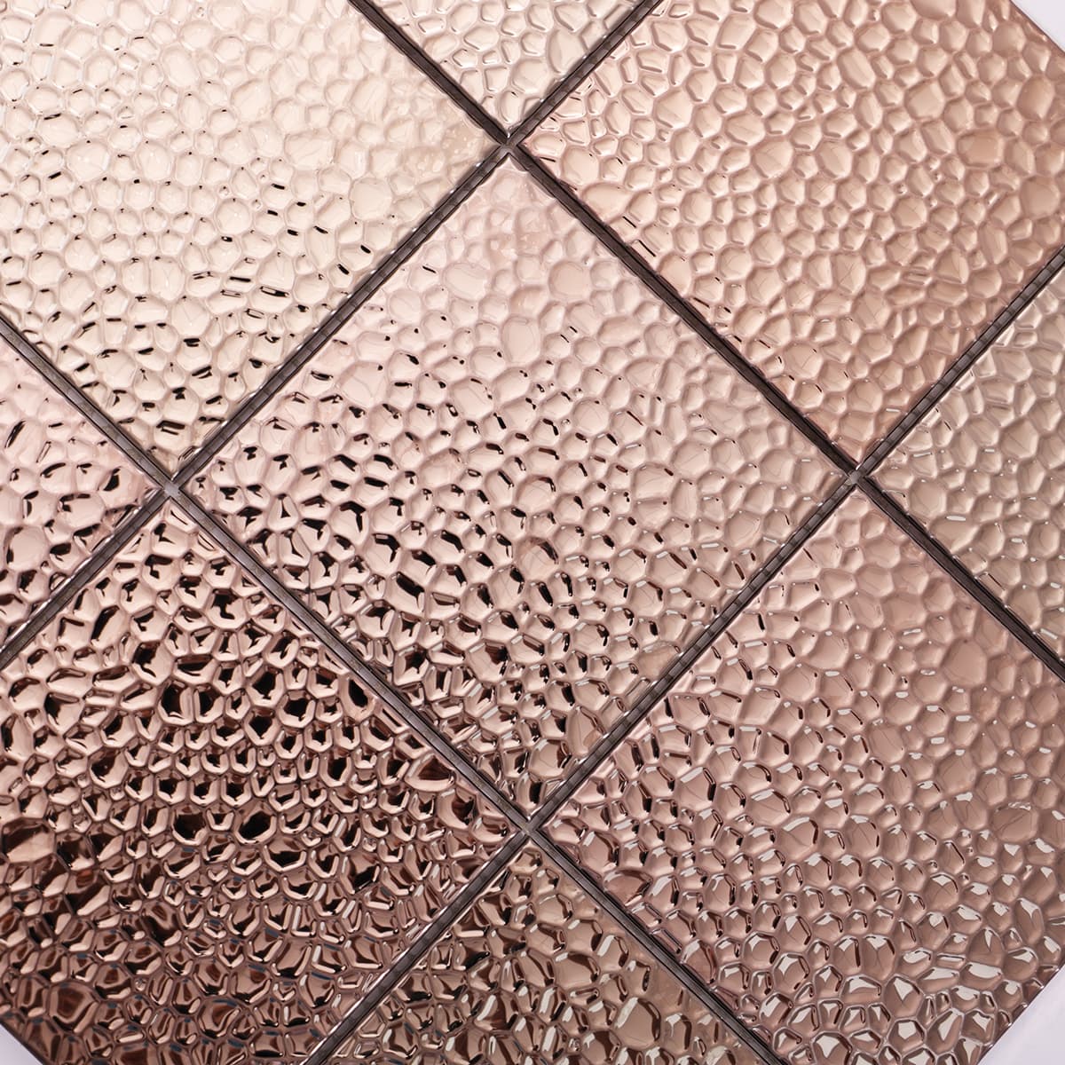 Angled view of rose gold hammered stainless steel mosaic for walls