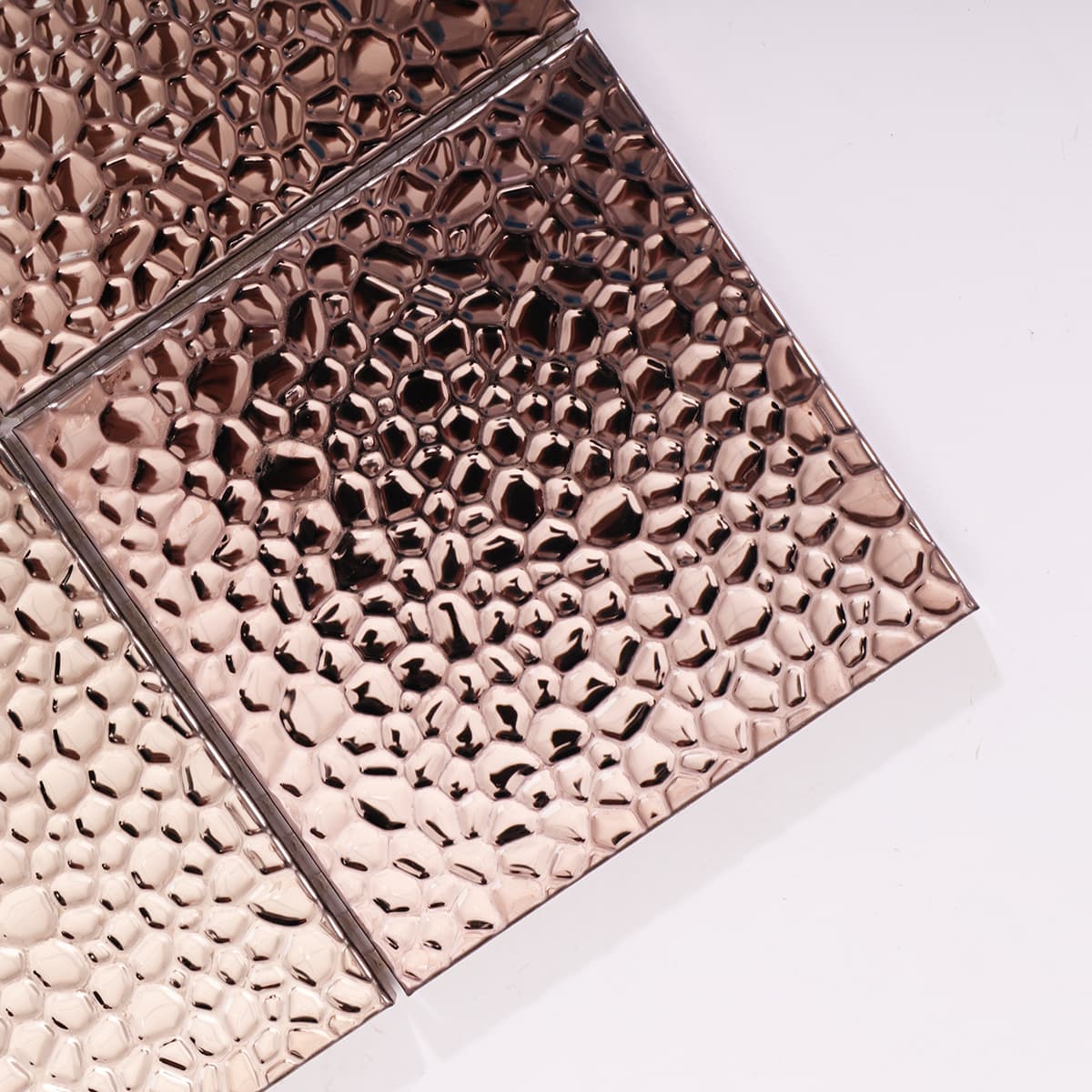 Close-up of rose gold hammered stainless steel tile with 3D texture