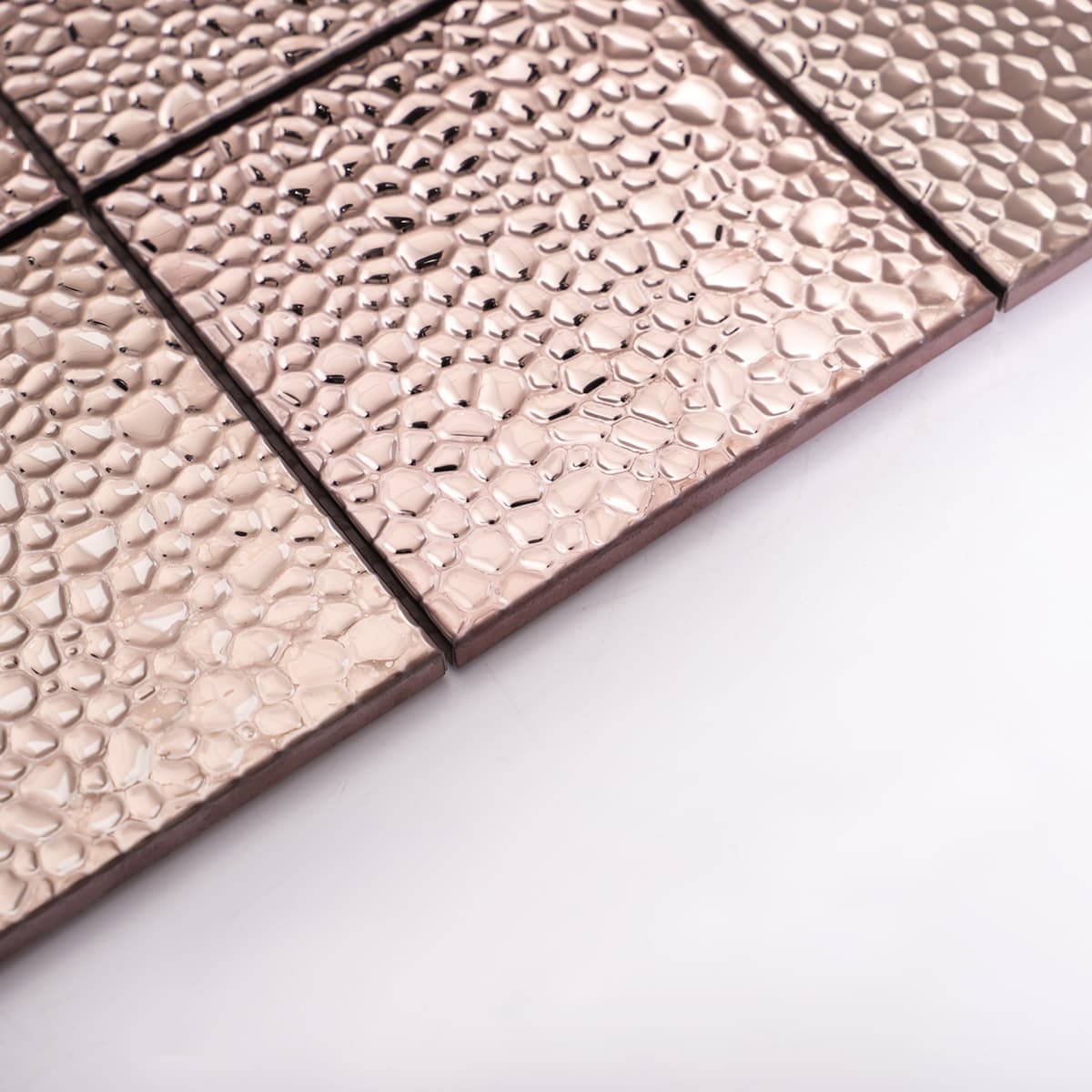 Edge detail of rose gold hammered stainless steel mosaic tiles