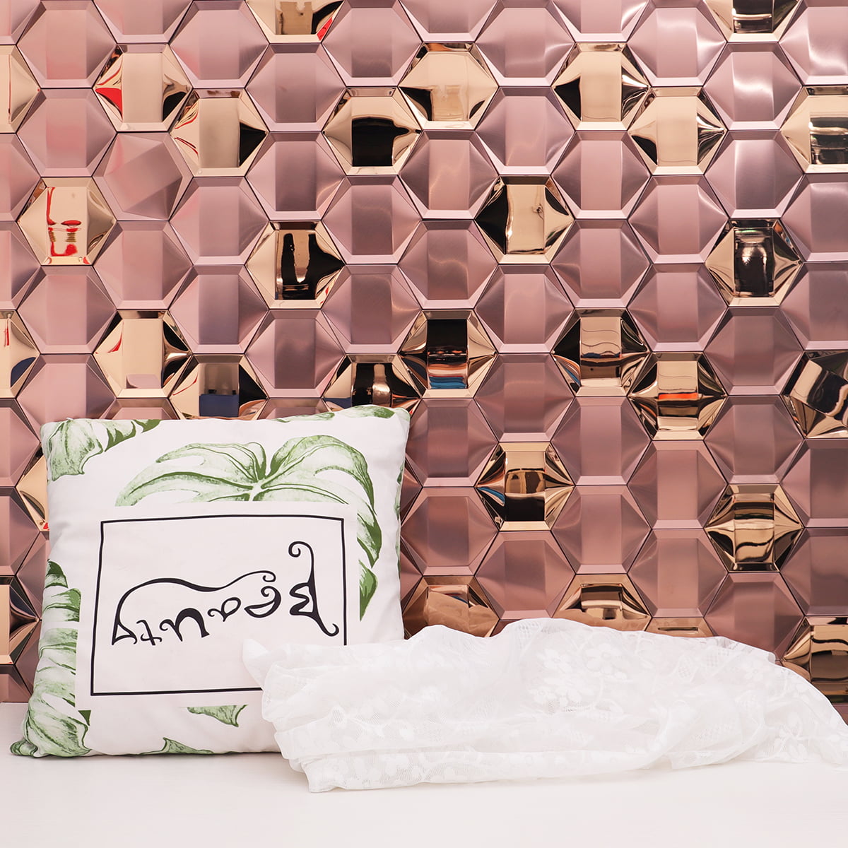  Rose gold hexagonal tiles arranged on a wall with decorative pillow and lace fabric in front 