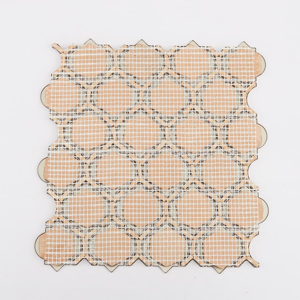 The back of a rose gold mosaic tile sheet showing the white mesh support.