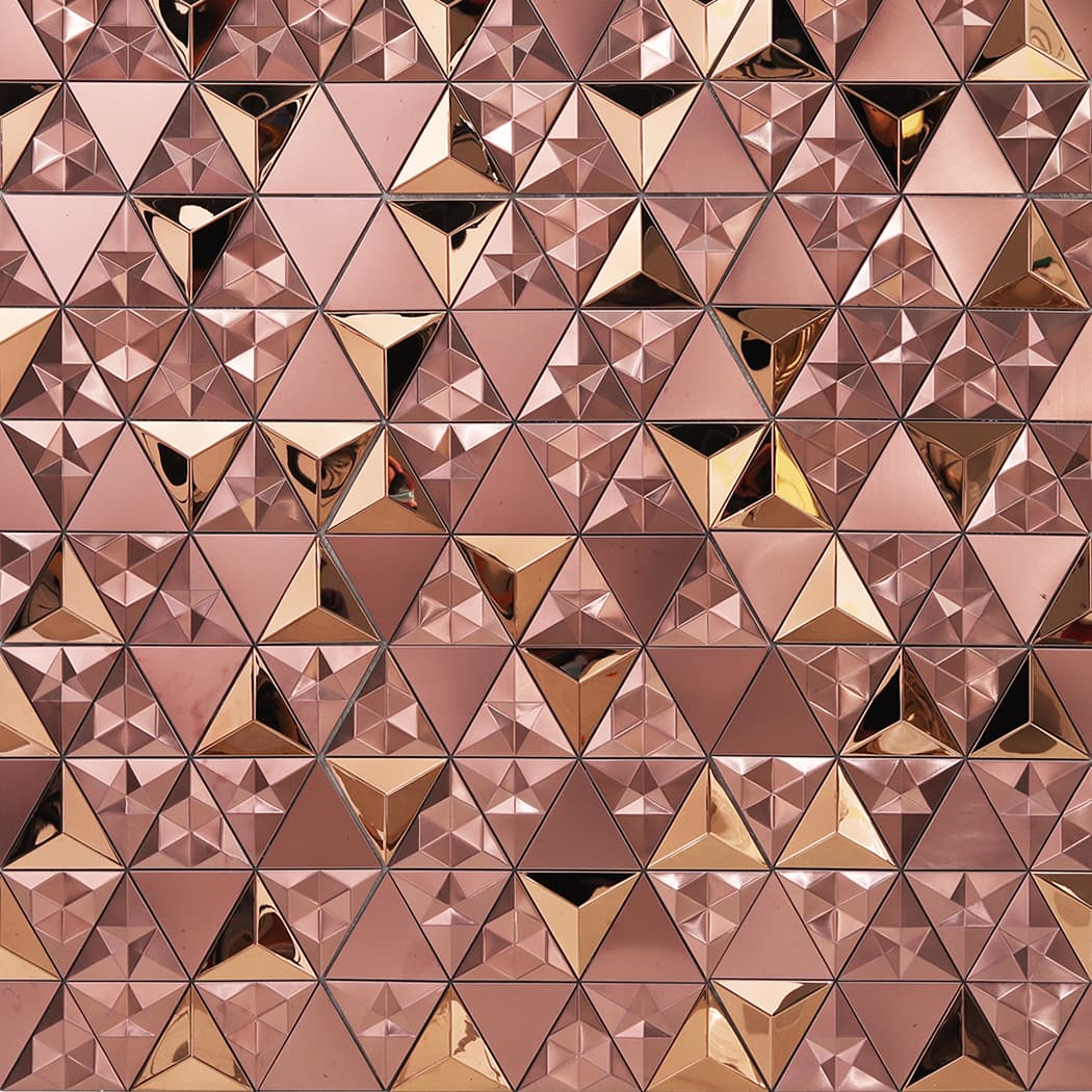 A full wall pattern of interlocking rose gold 3D triangular mosaic tiles.