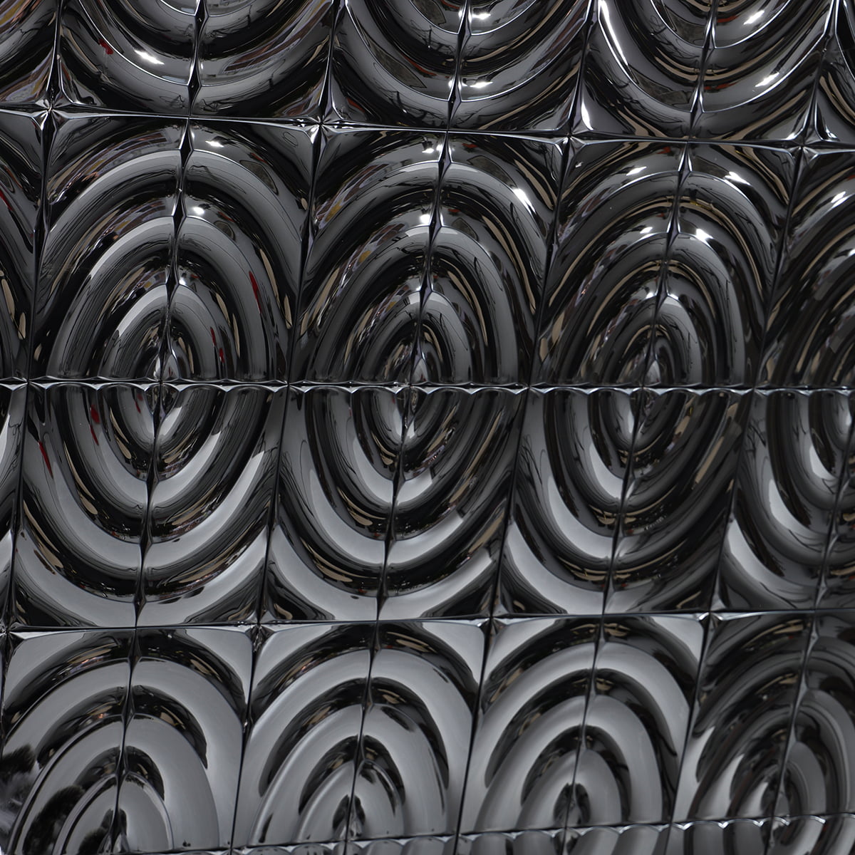 A close-up of metallic tiles with shiny wavy patterns arranged in a grid 