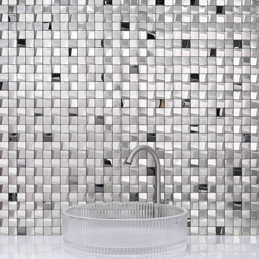 Straight on view of a glass vessel sink and faucet against a silver 3D metal mosaic wall.