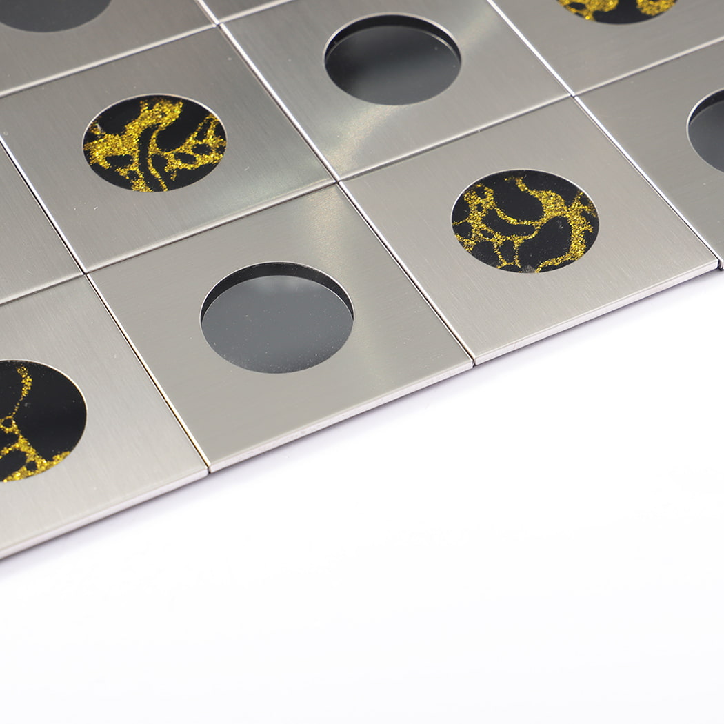 Edge detail of silver stainless steel tile featuring round mirrors and gold veins.