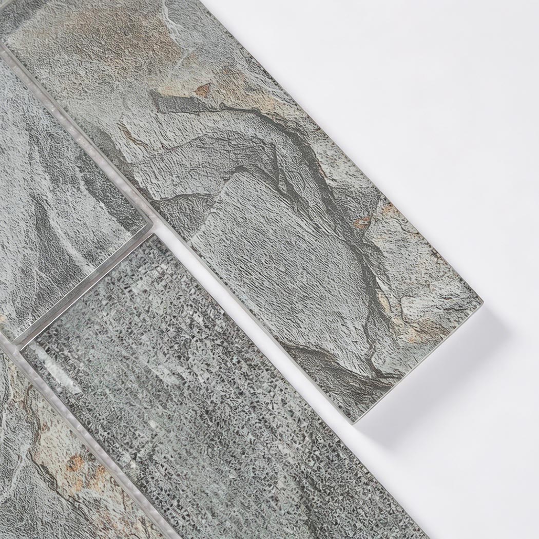 Angled close up view of slate grey and brown textured glass mosaic tiles.