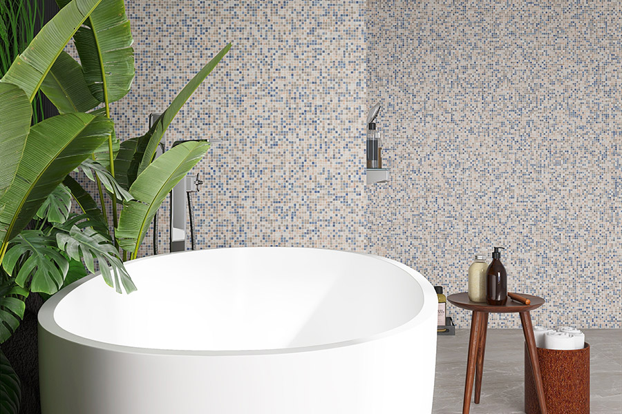 Modern bathroom featuring small blue mosaic tile wall, white tub, and green plants.