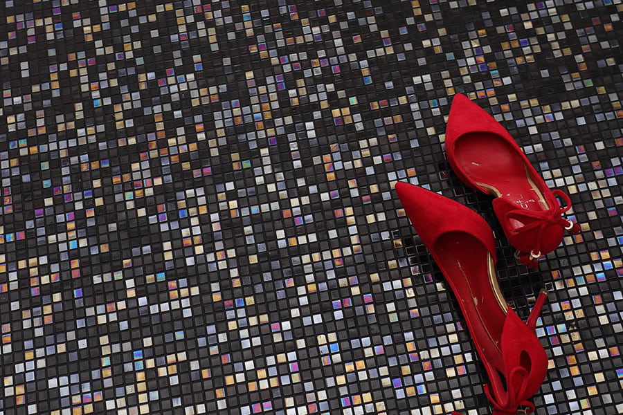 Black iridescent small mosaic floor tiles with red shoes on top