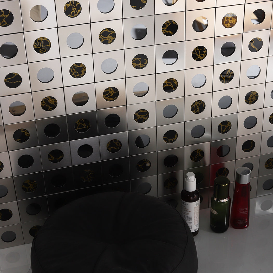 Interior display of round mirror stainless steel tiles with gold pattern reflection.