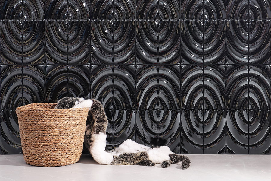 Textured black 3D circular relief tile wall with a basket holding a faux fur blanket