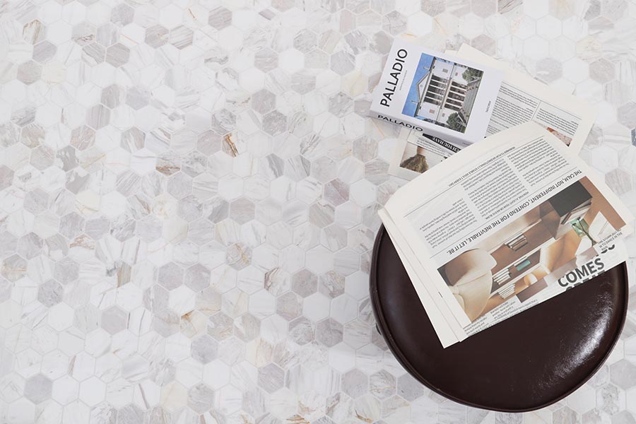 Mosaic floor tiles in white and gray hexagon marble with a round table and open magazines