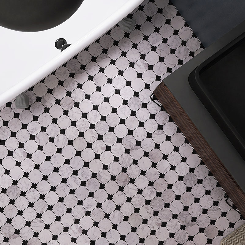 Close view of white marble bathroom floor tile with black quatrefoil accents
