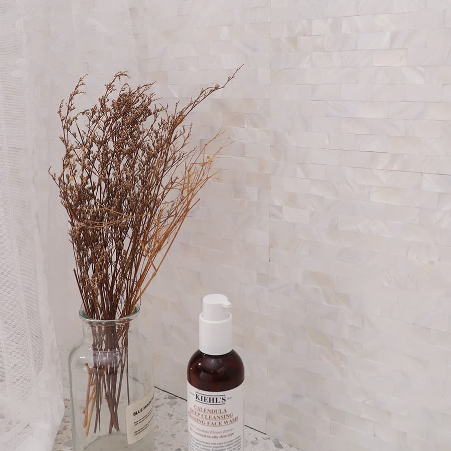 Vertical view of pearl mosaic tile with skincare and dried bouquet