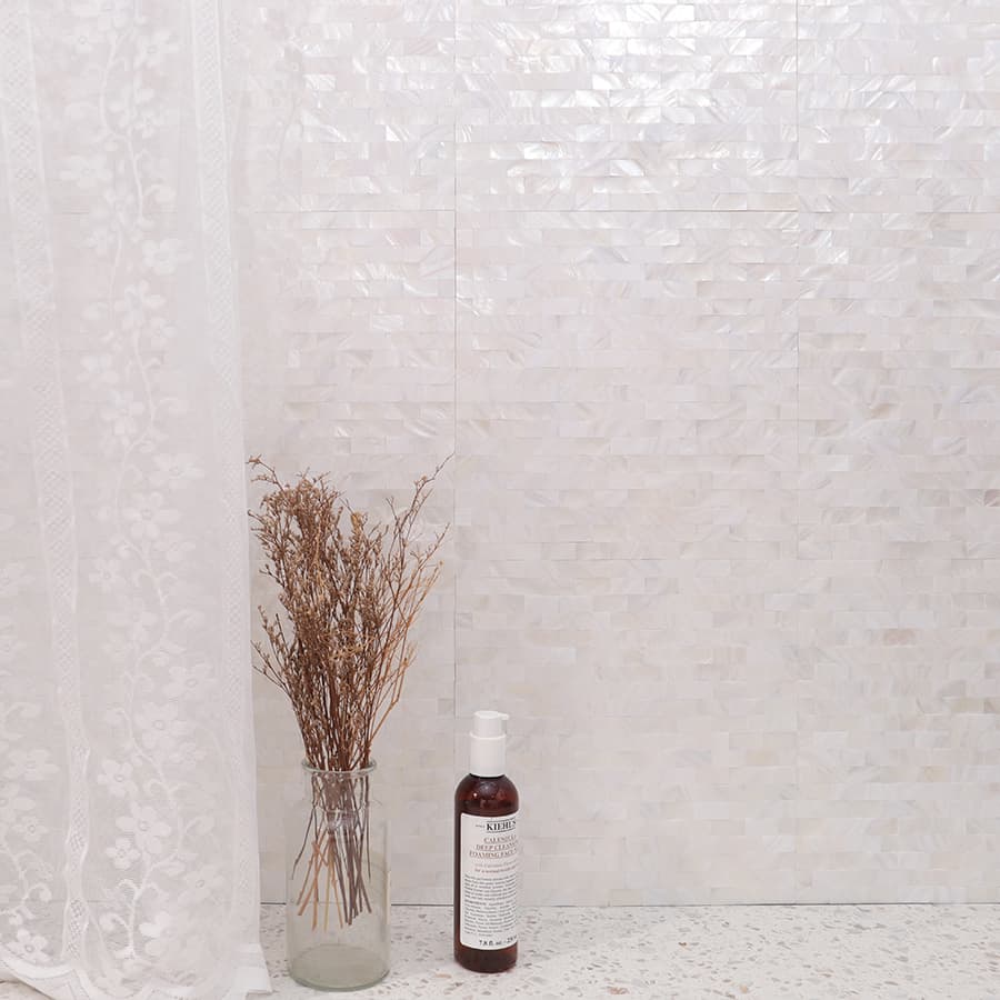 White pearl strip mosaic tile wall with curtain, bottle and dried flower