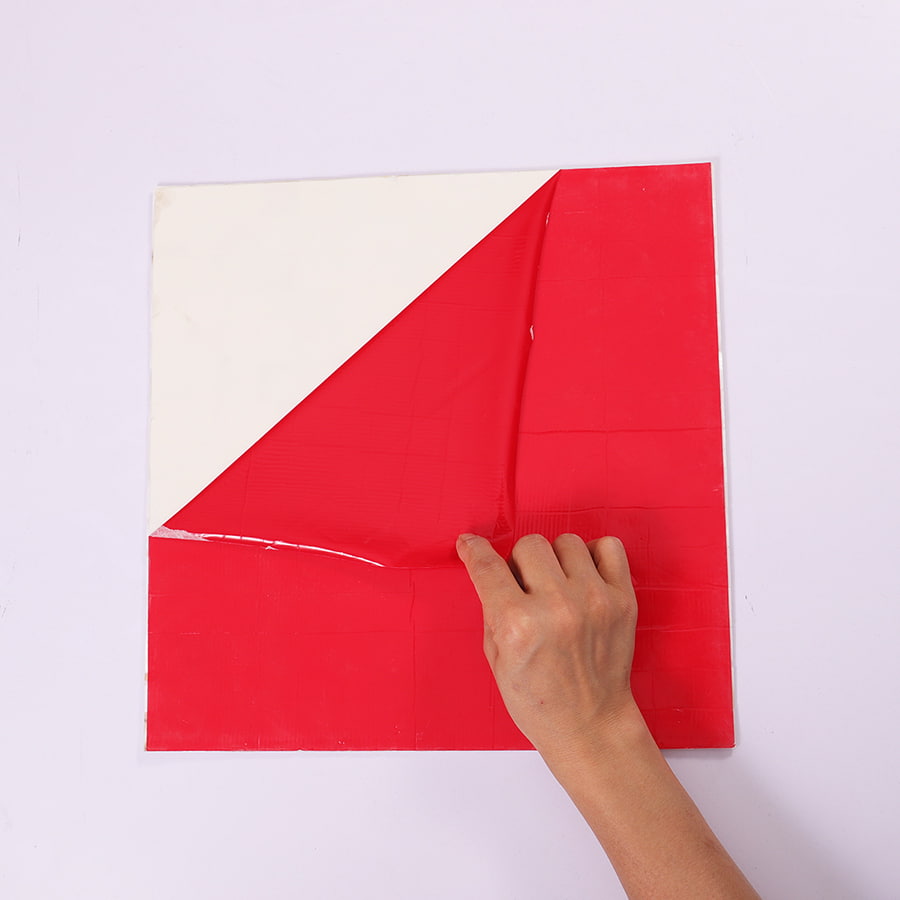 Backside of white shell mosaic tile with red adhesive film partially peeled