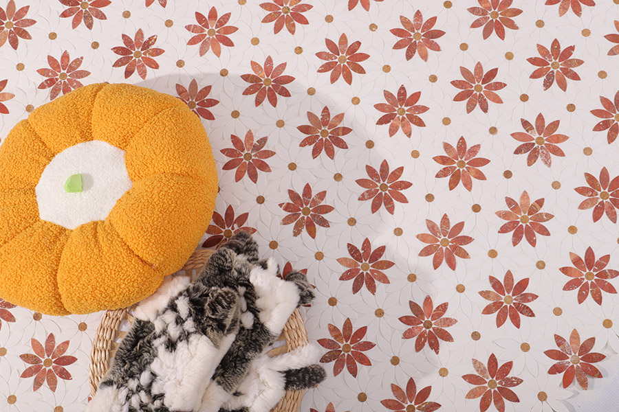 Wide view of white and terracotta daisy mosaic floor tile with a cushion and fur throw