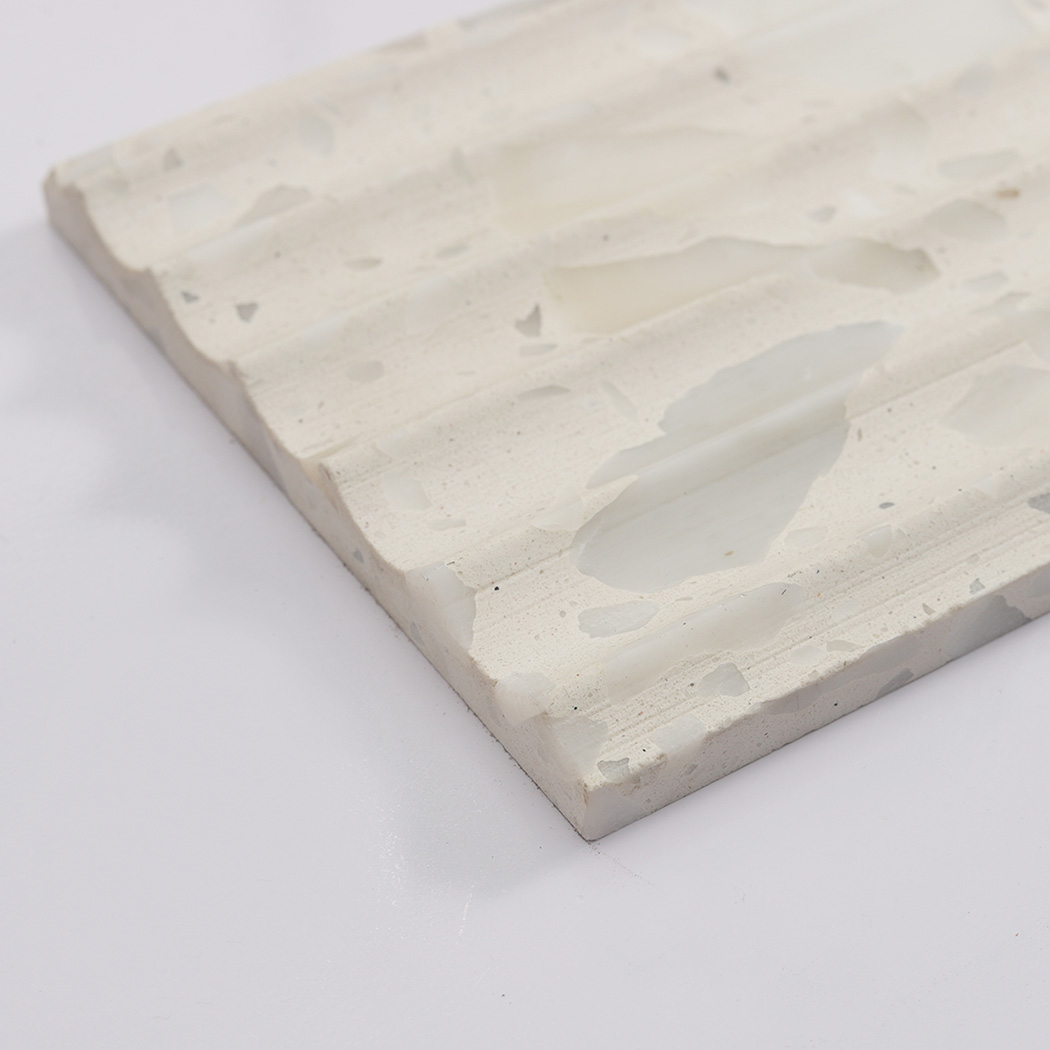 Angled edge detail of white terrazzo fluted tile with natural chip texture