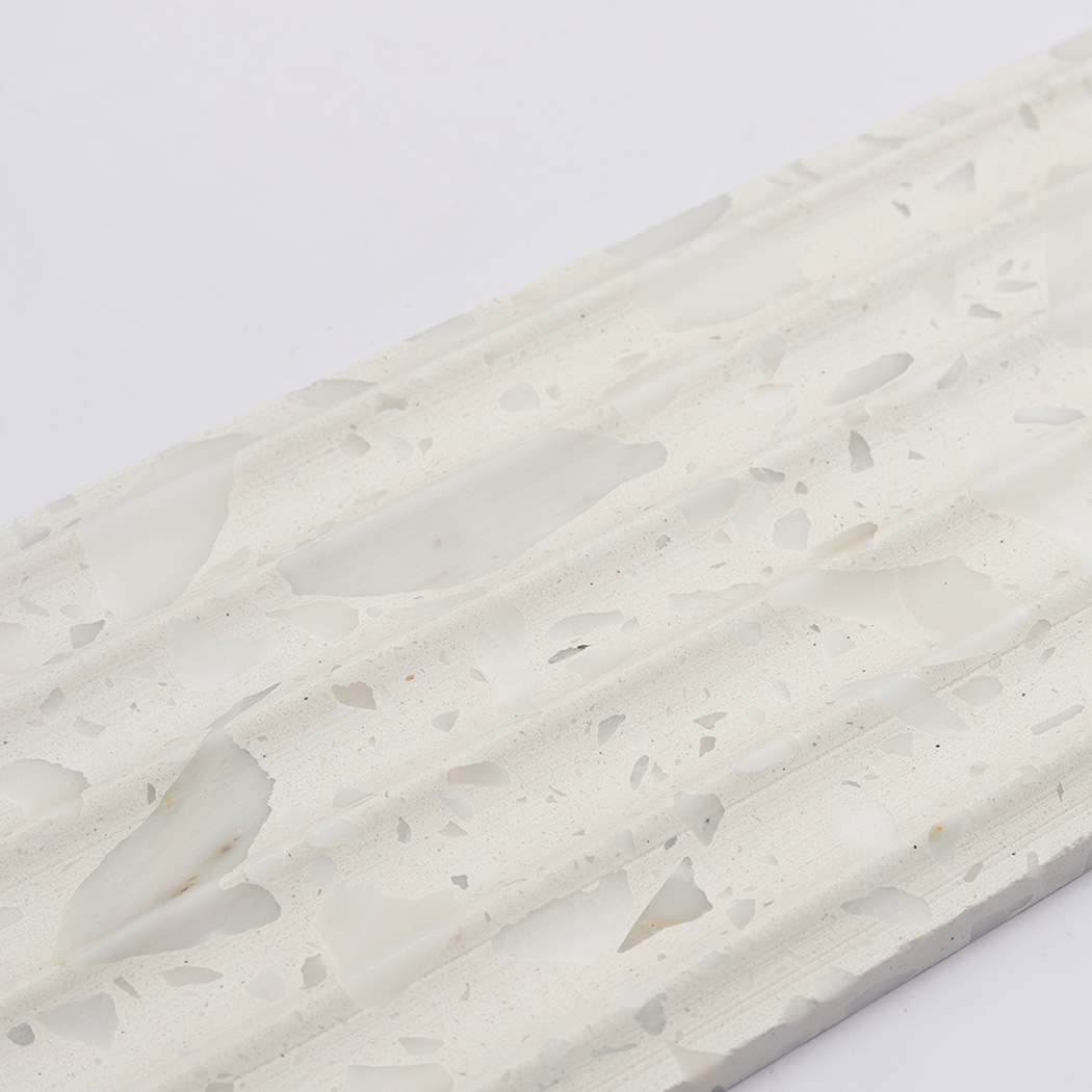 Close up of white terrazzo fluted tile with pale gray stone fragments