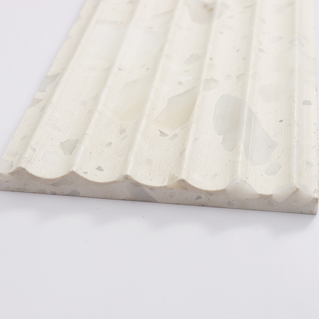 Rounded fluted profile of white terrazzo tile with soft marble chip pattern