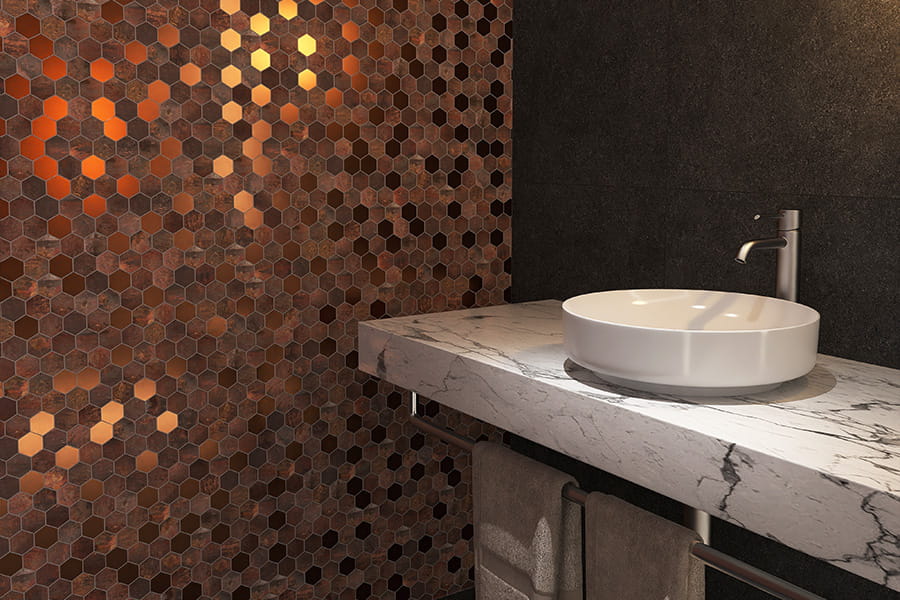 Wide view of copper hexagon mosaic tile wall next to stone and black tiles 