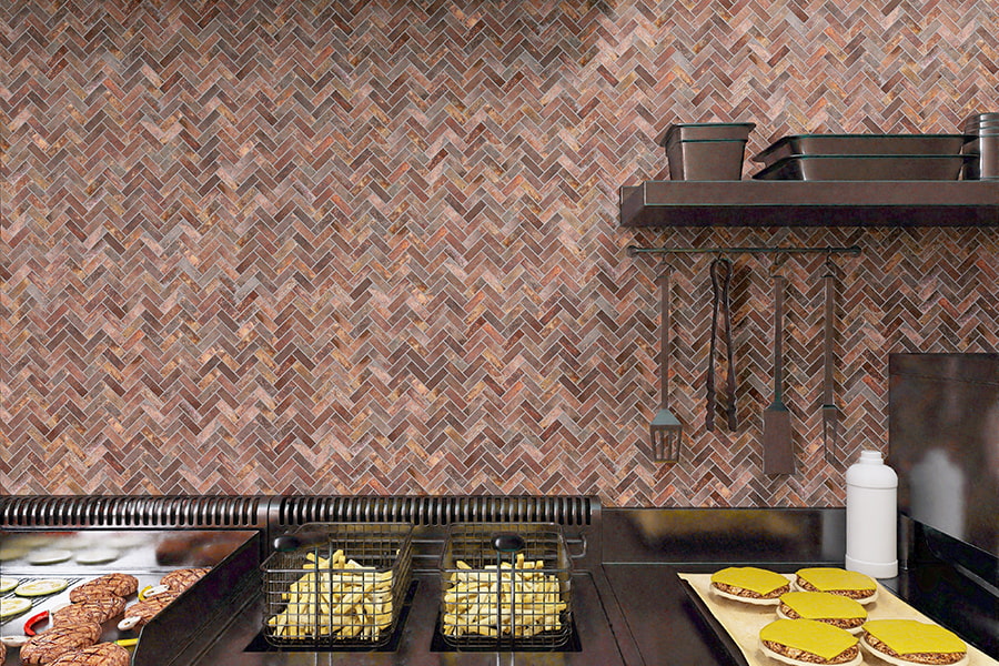 Wide view of stove, fryer baskets, and burgers with herringbone tile backsplash