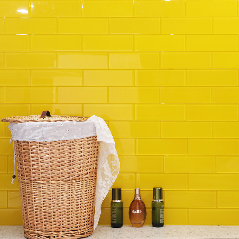 Bright yellow kitchen tiles behind a wicker basket and vanity countertop accessories.