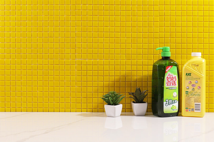 Yellow mosaic backsplash tiles with green soap bottles and potted plants