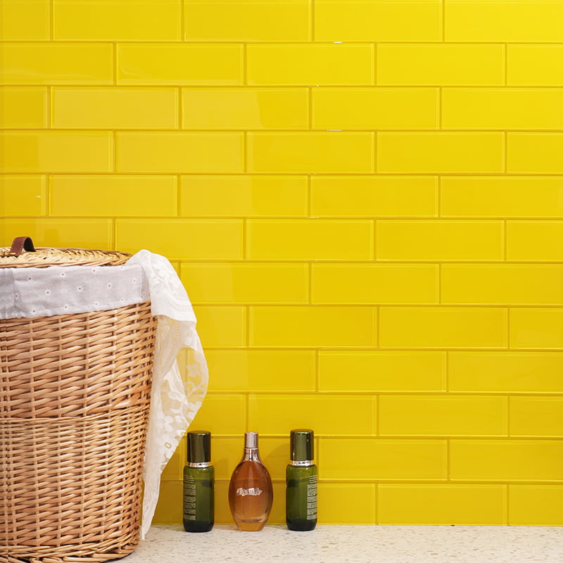 Yellow long subway tiles in horizontal stacked pattern with laundry basket and toiletries