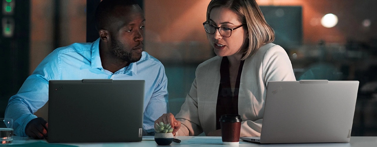 Front view of two professionals sitting in a meeting room & discussing work using the Lenovo ThinkPad T14s Gen5 (14&rdquo; Intel) laptops in Eclipse Black & Luna Grey colors, highlighting its business usecase.