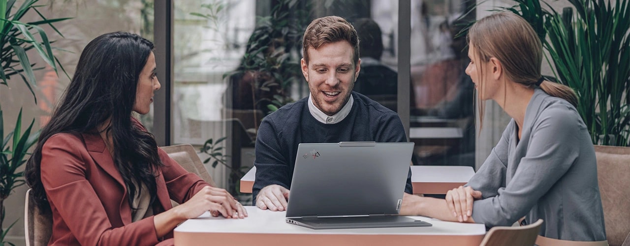 Rear-view of the Lenovo ThinkPad X1 2-in-1 convertible laptop on a table, open in stand mode with 3 people sitting around it.