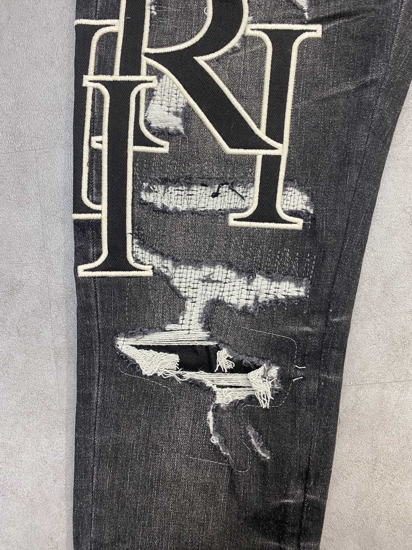 AMIRI jeans with a distressed finish, embroidered logo on the side (ADS050-033）