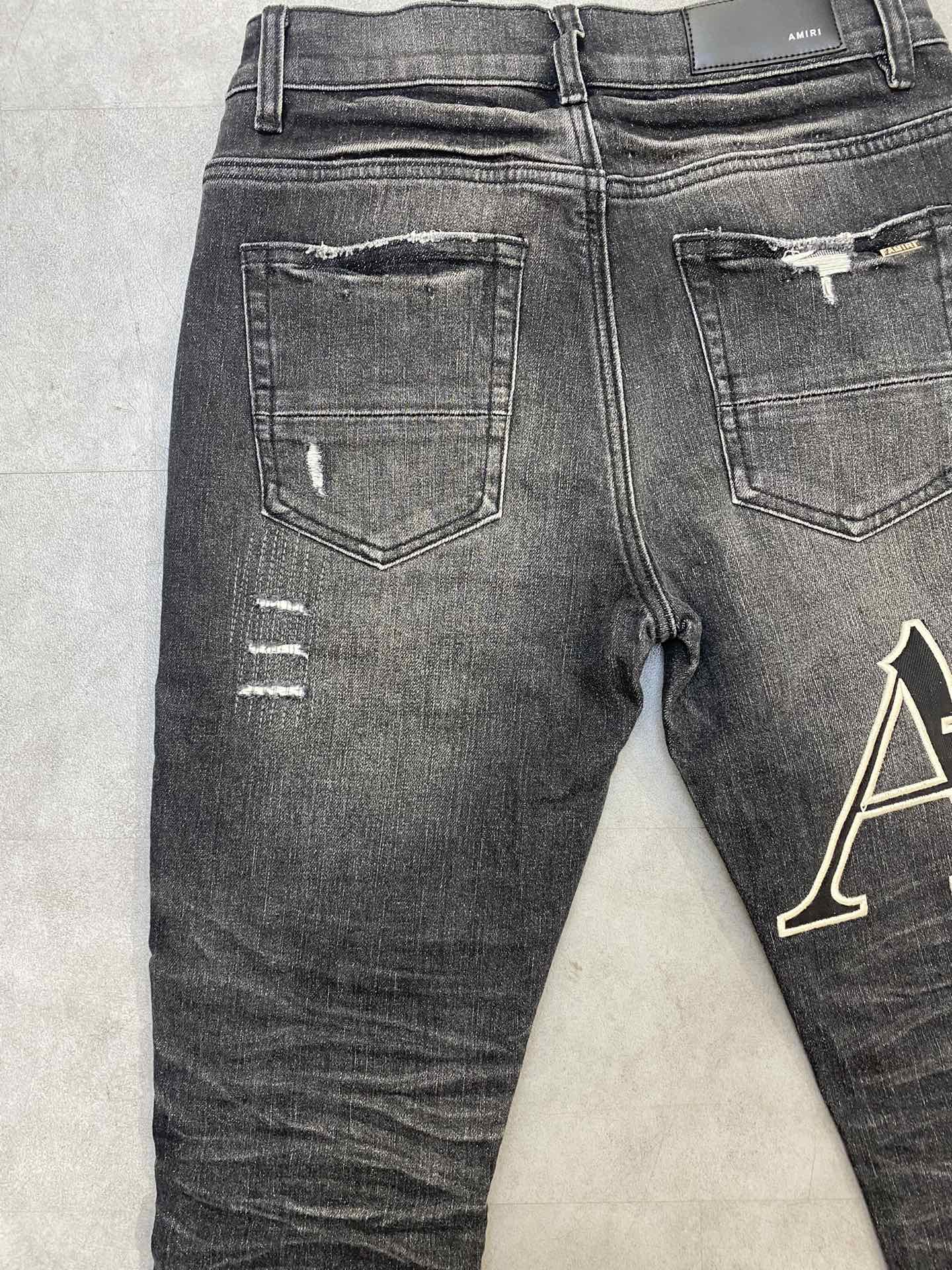 AMIRI jeans with a distressed finish, embroidered logo on the side (ADS050-033）