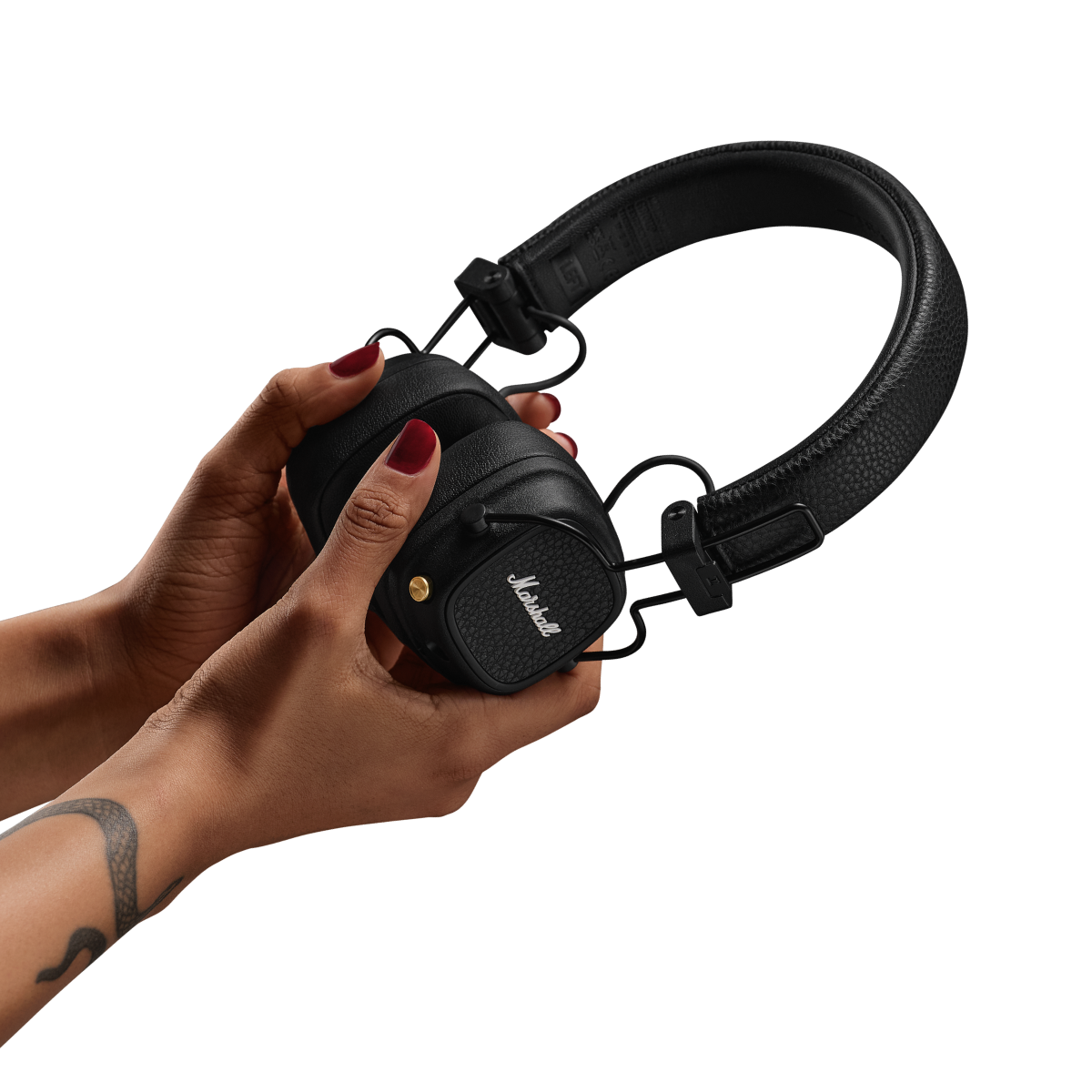 Woman holding a pair of black Marshall Major V on-ear headphones against a dark background.
