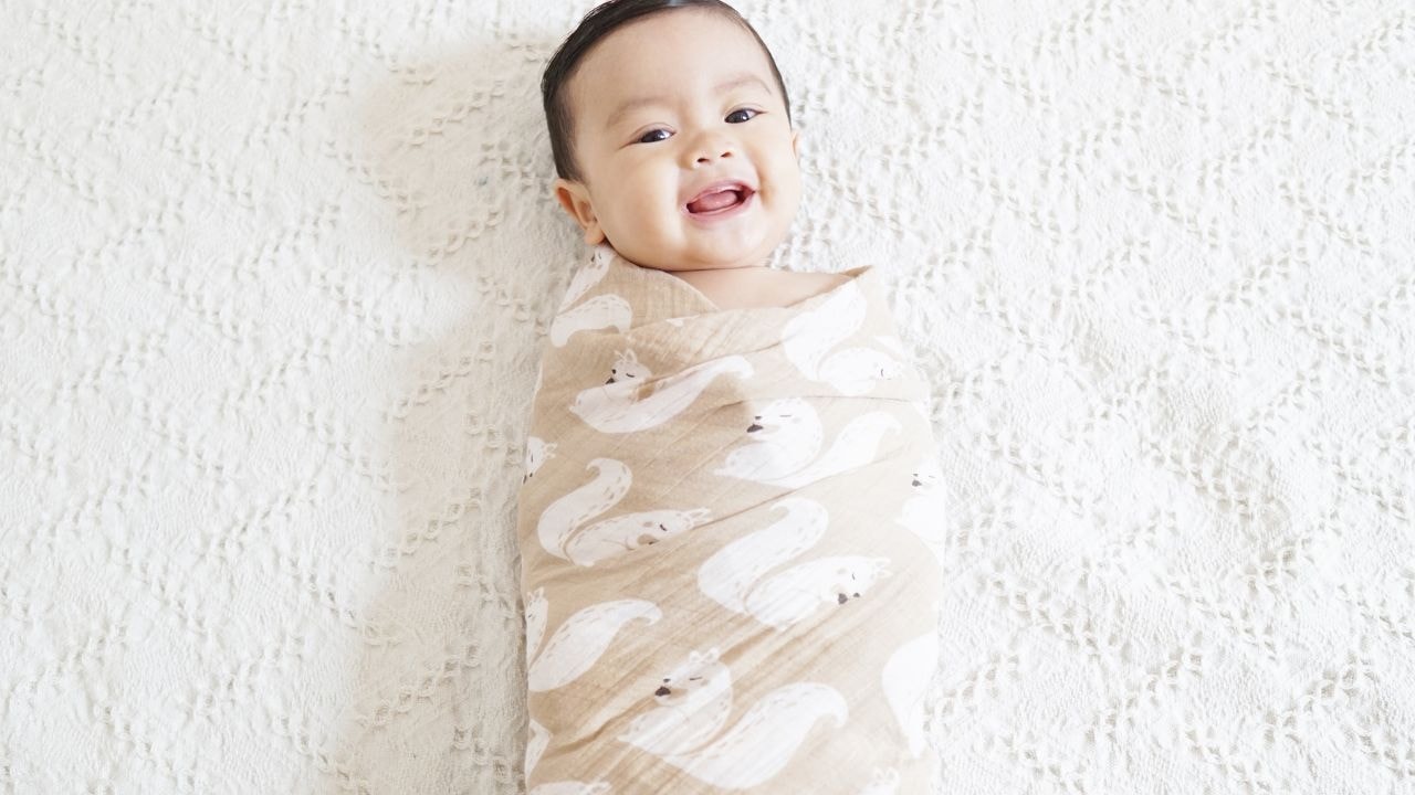 Baby wrapped snugly showing a the happiest baby times in a traditional swaddle blankets