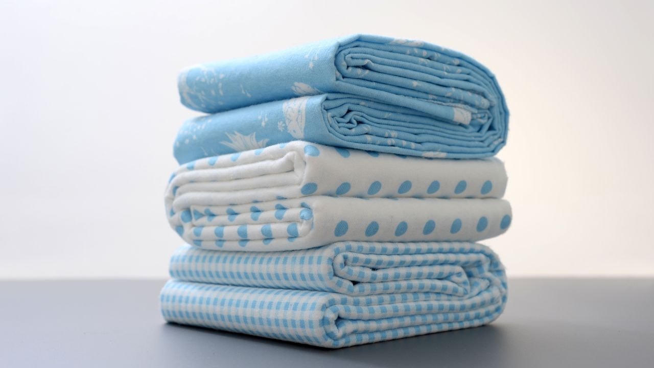 A stack of soft, organic cotton baby swaddles in blue, perfect for keeping babies warm and cozy