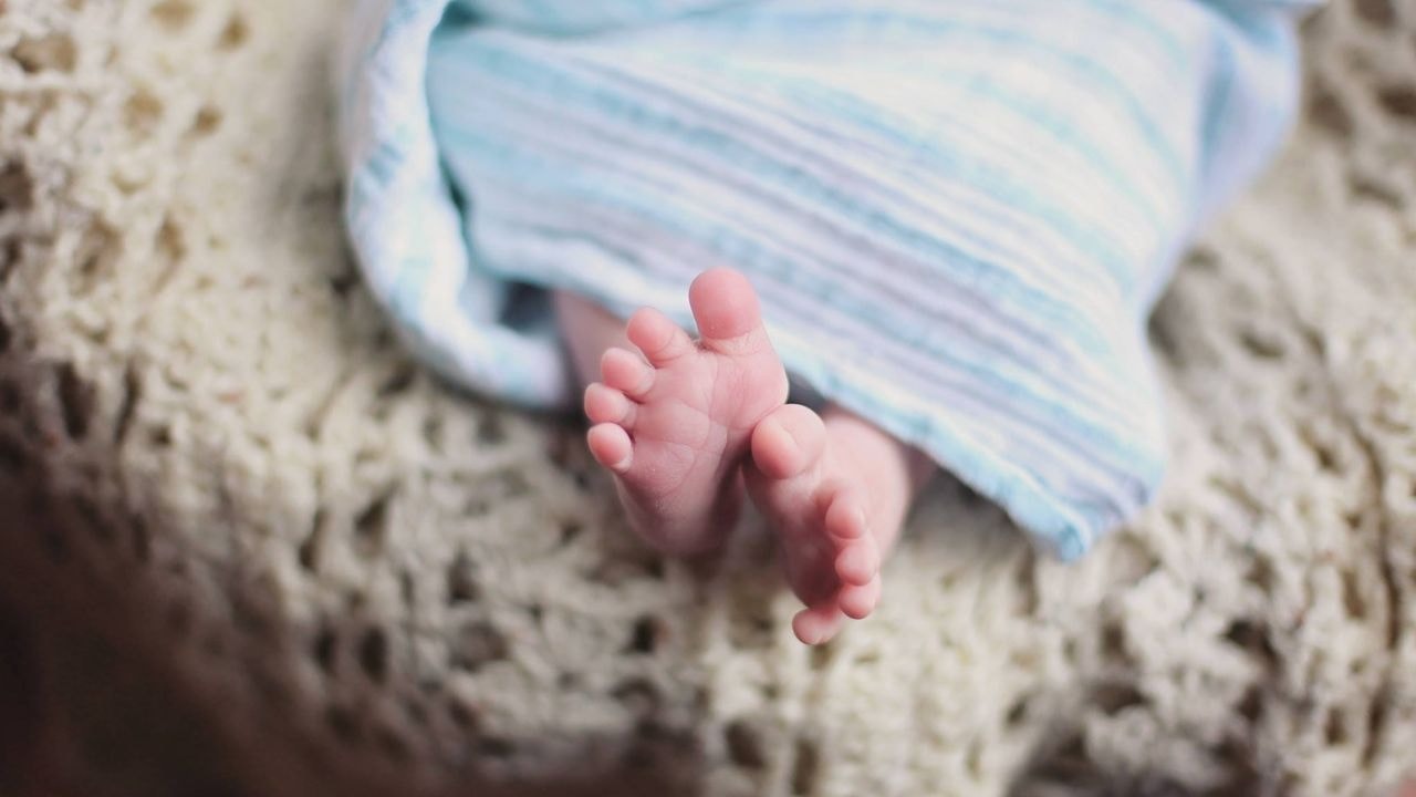 Newborn&rsquo;s feet peeking out from a swaddling blanket