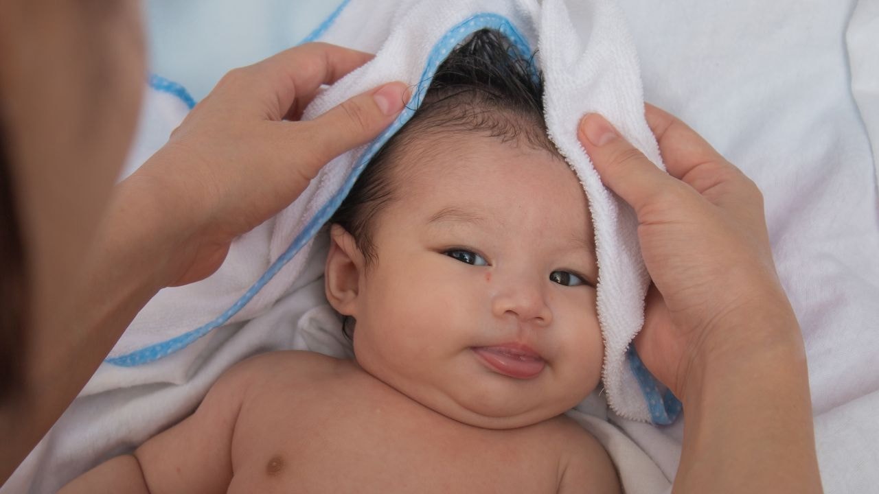  A parent gently wrapping a hooded baby towel around their baby