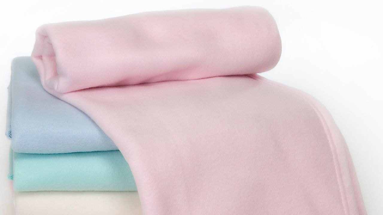  A stack of differnt sized pastel-colored, soft baby blankets