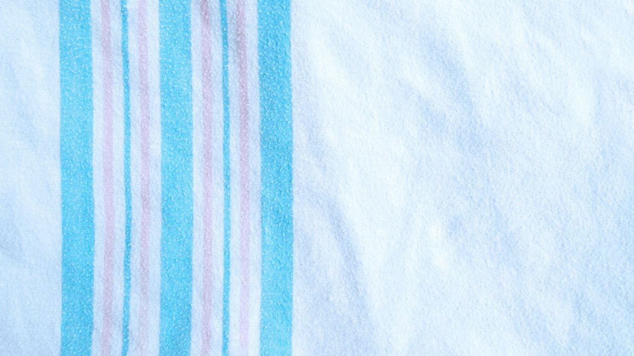 A close-up of a striped receiving baby blanket, ideal for use in a stroller or car seat