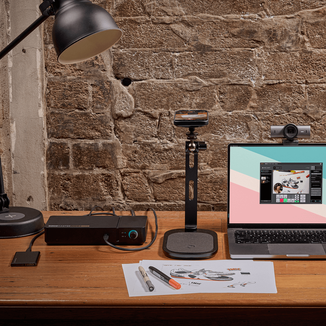 Person using PodMic USB and RØDECaster Video desk setup