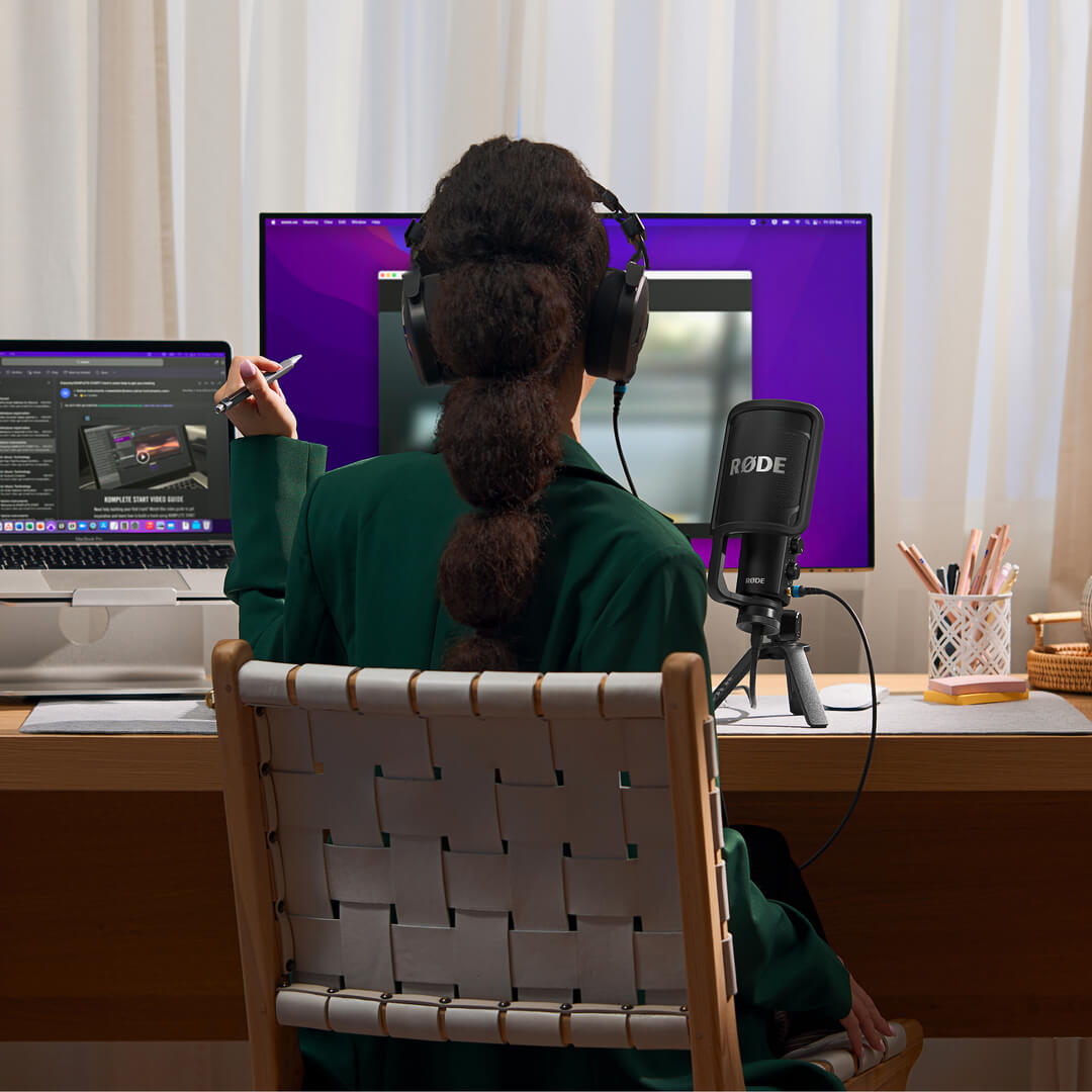 Girl at desk wearing NTH-100 and holding pencil in front of computer screen with NT-USB+ next to her