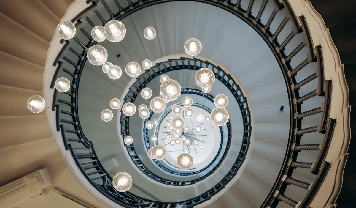 Artistic lighting design featuring cascading glass orbs suspended in a spiral staircase, perfect for vertical and high-ceiling spaces.