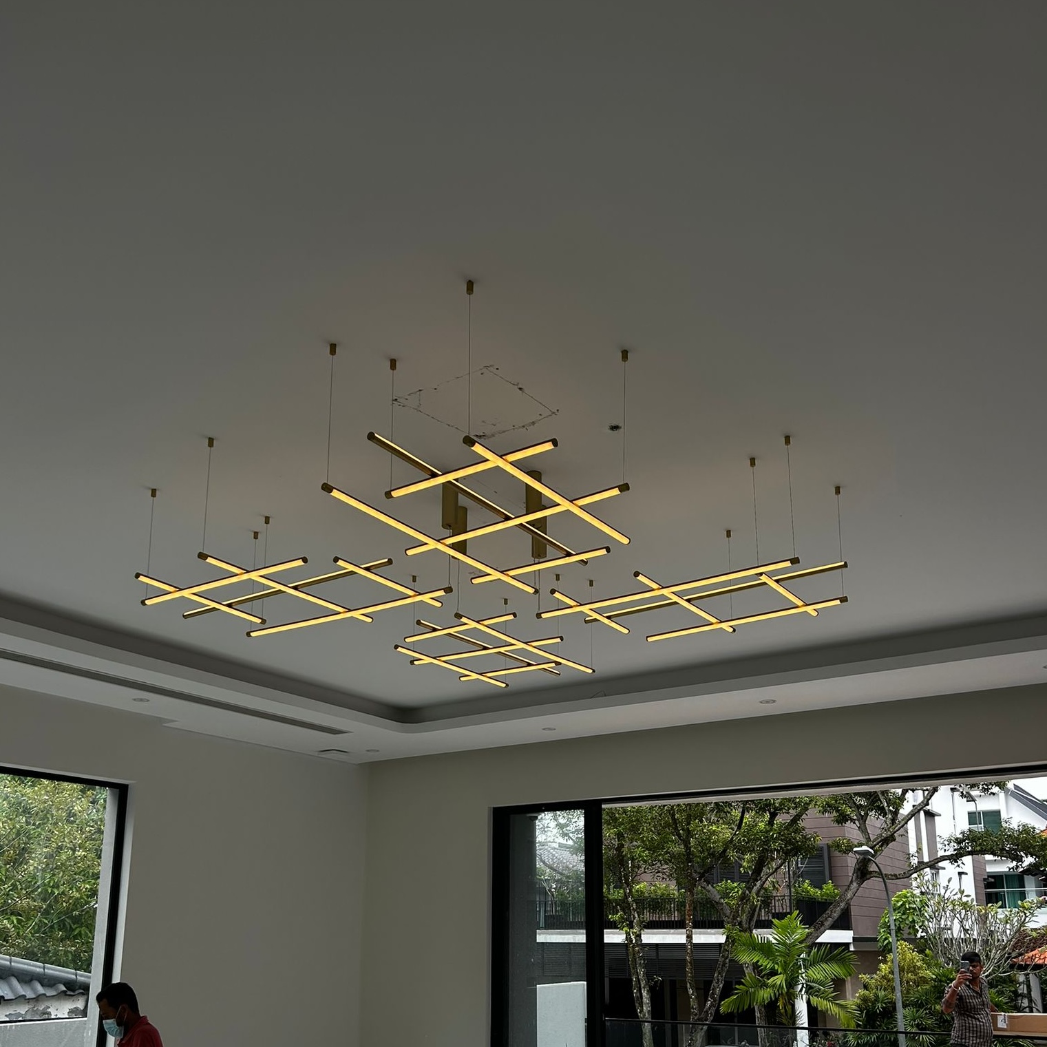 Modern geometric pendant light with gold accents suspended in a high-ceiling living space.