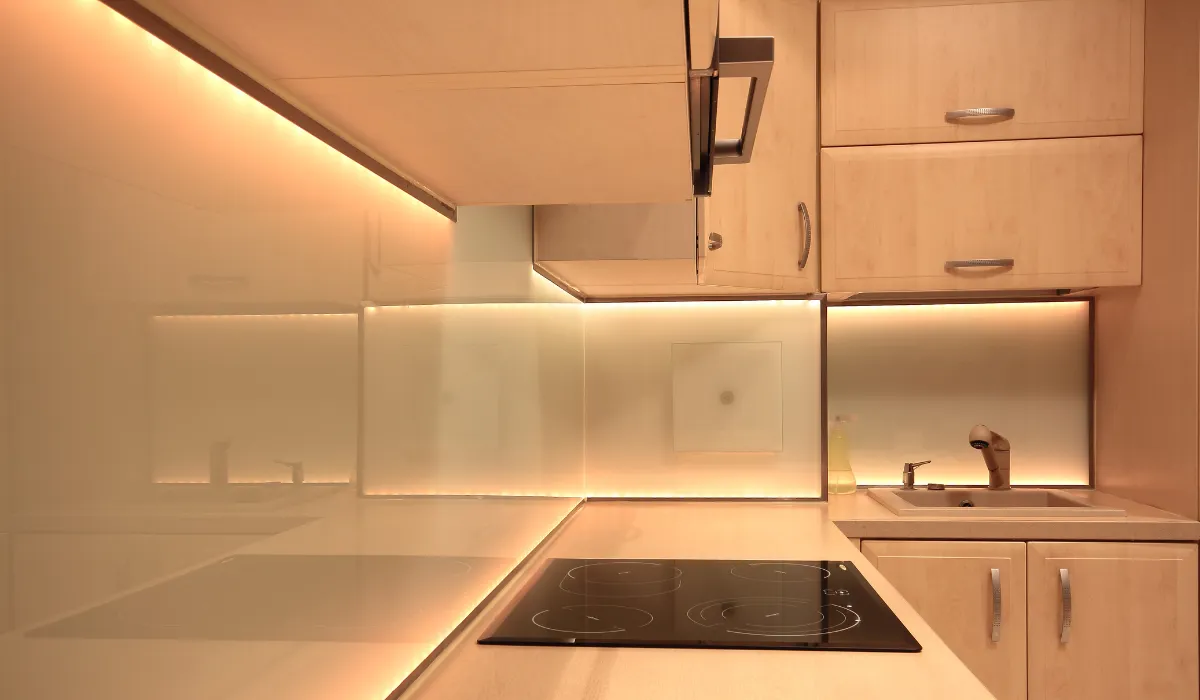Minimalist kitchen with soft under-cabinet lighting and light wood cabinetry.
