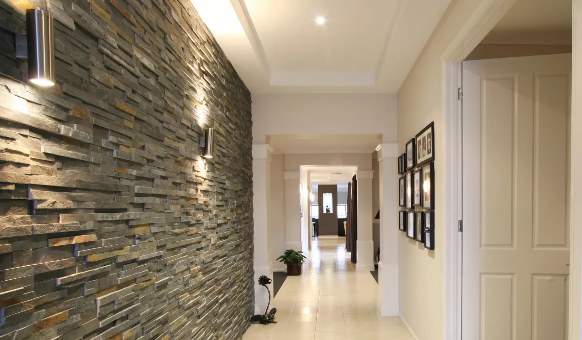 Contemporary hallway featuring a textured stone wall lit by sleek wall sconces