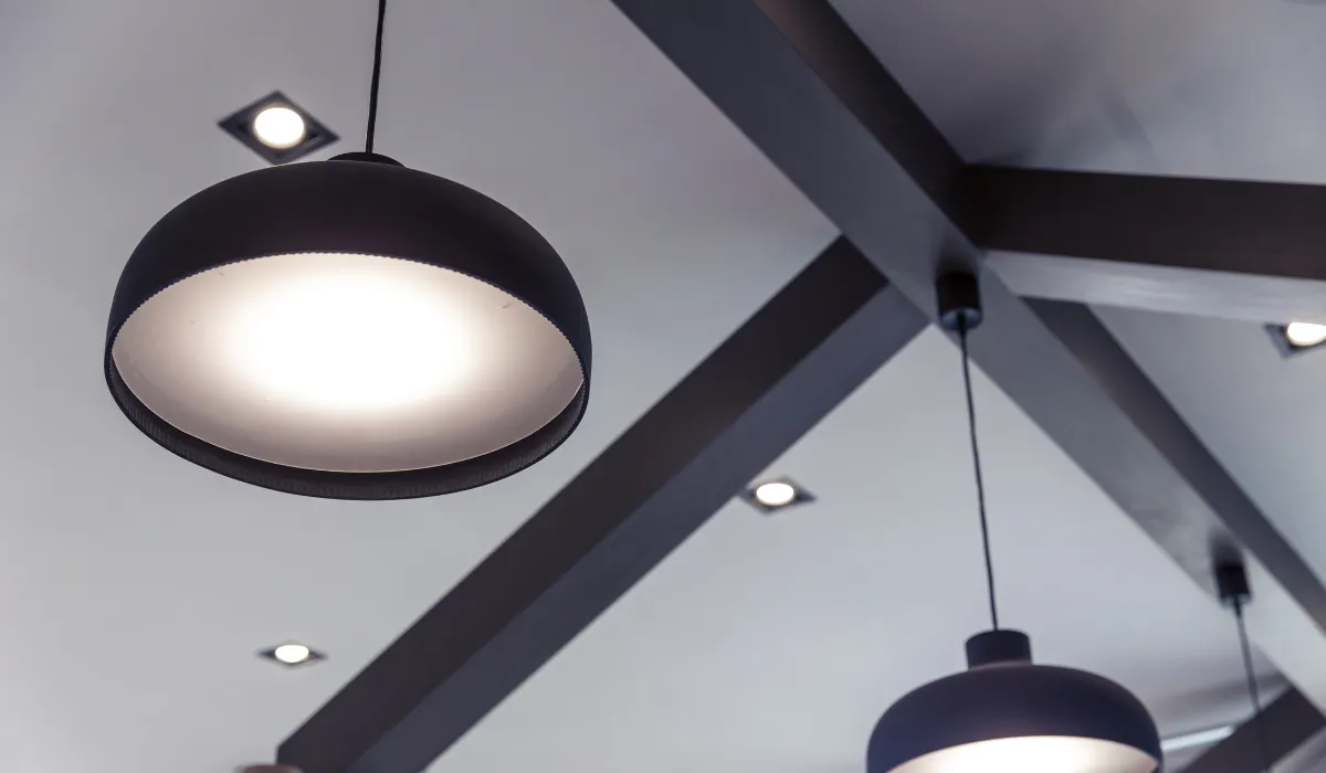 Modern black pendant light with recessed ceiling spotlights, providing balanced ambient lighting in a contemporary interior.